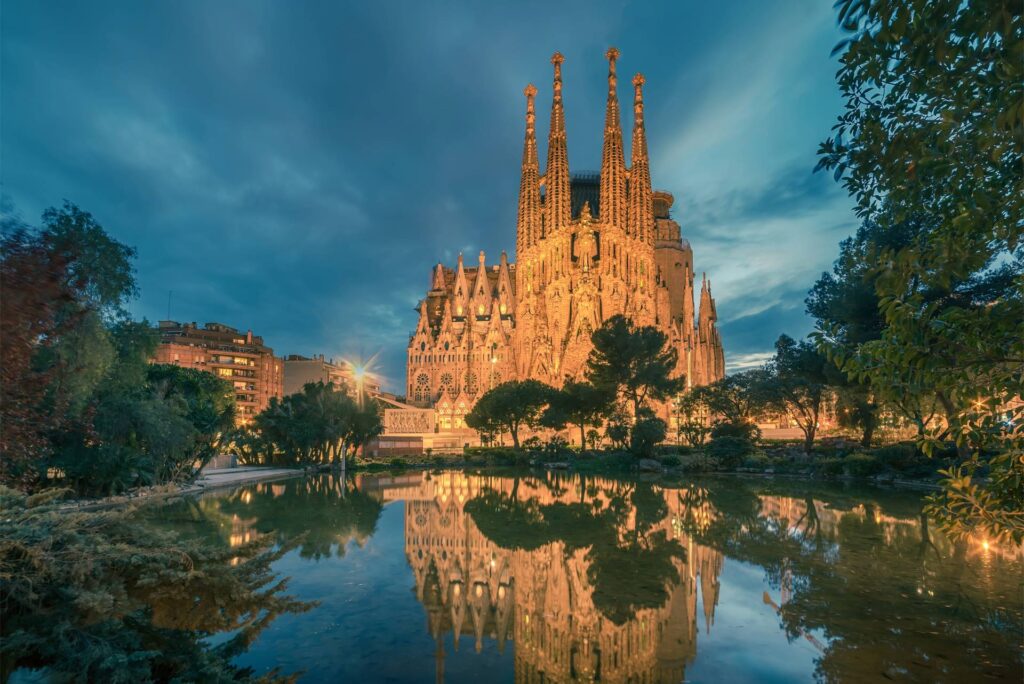 Sagrada Familia iluminada al crepúsculo con reflejos.