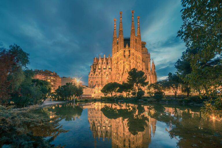 Sagrada Familia illuminated at twilight with reflection.